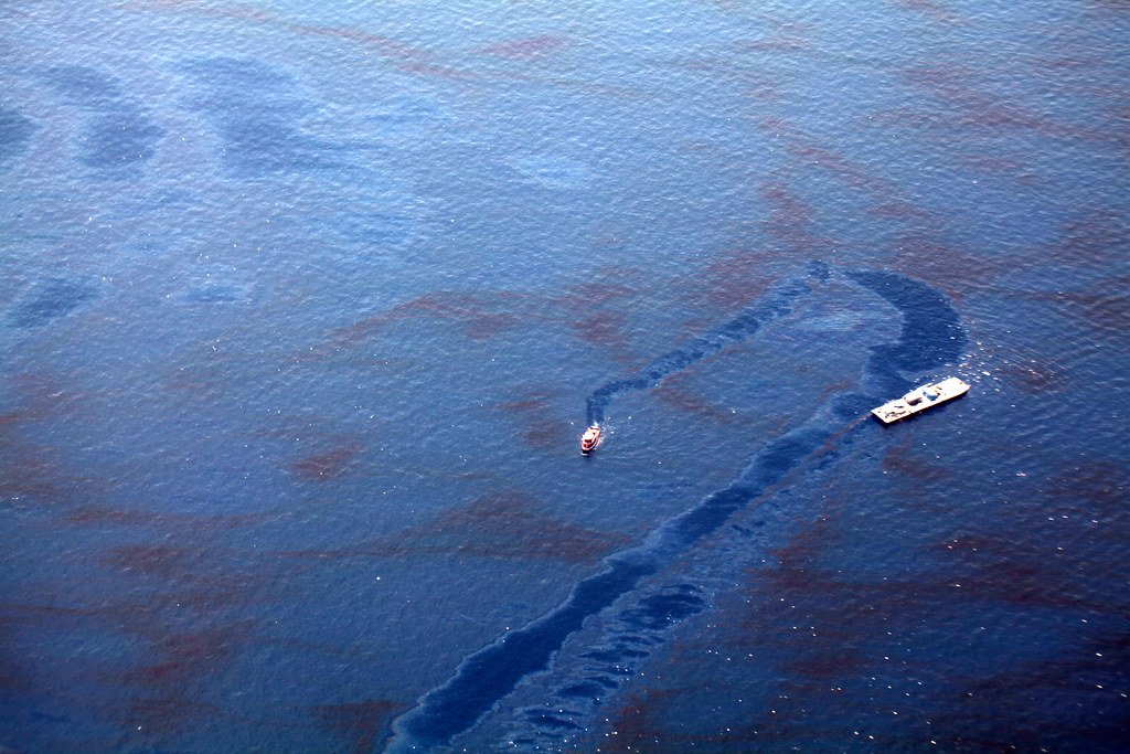 Liquid spilling across pavement near a drain, illustrating an unauthorized discharge.